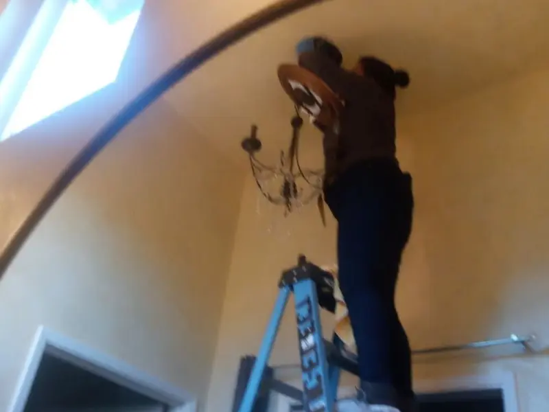 Electrician installing a chandelier in a Wilkins residence